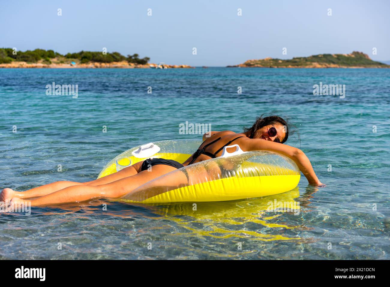 Back view of a woman on a donut inflatable pillow on turquoise water Stock Photo