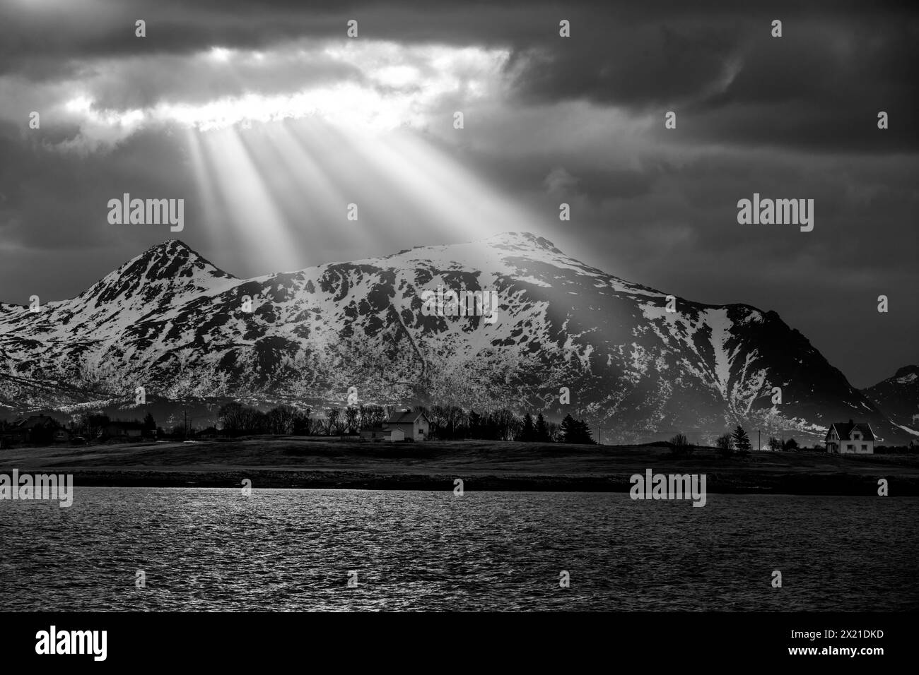 Sunrays shine through hole in the clouds onto mountains and fjord, Skreda, Lofoten, Nordland, Norway Stock Photo