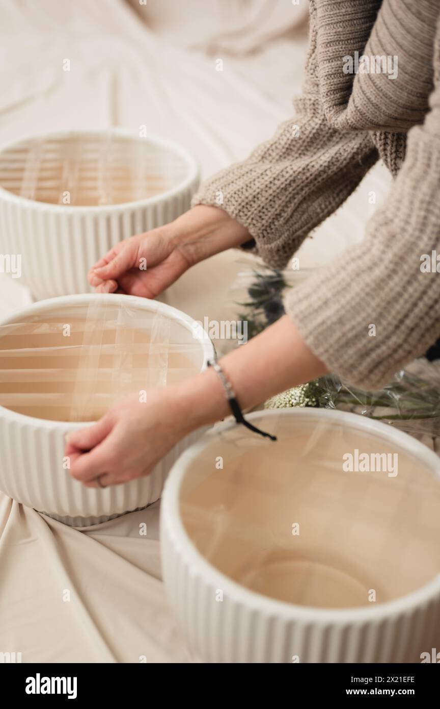 Florist taping vases using tape grid method to create floral bouquets Stock Photo