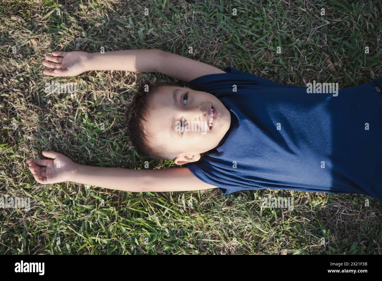 Little cute boy is lying on the green grass on a sunny day Stock Photo