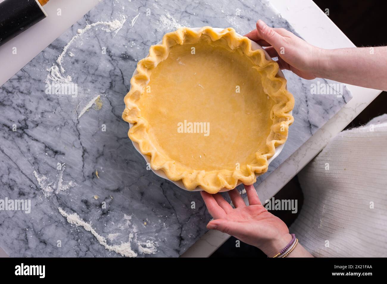 Preparing a fluted pie crust on a marble countertop Stock Photo - Alamy