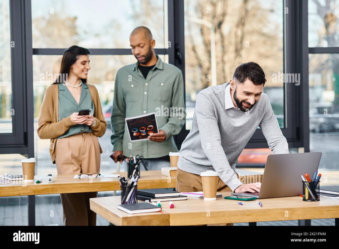 Two men and a woman collaborating on a project, deeply engaged with a ...