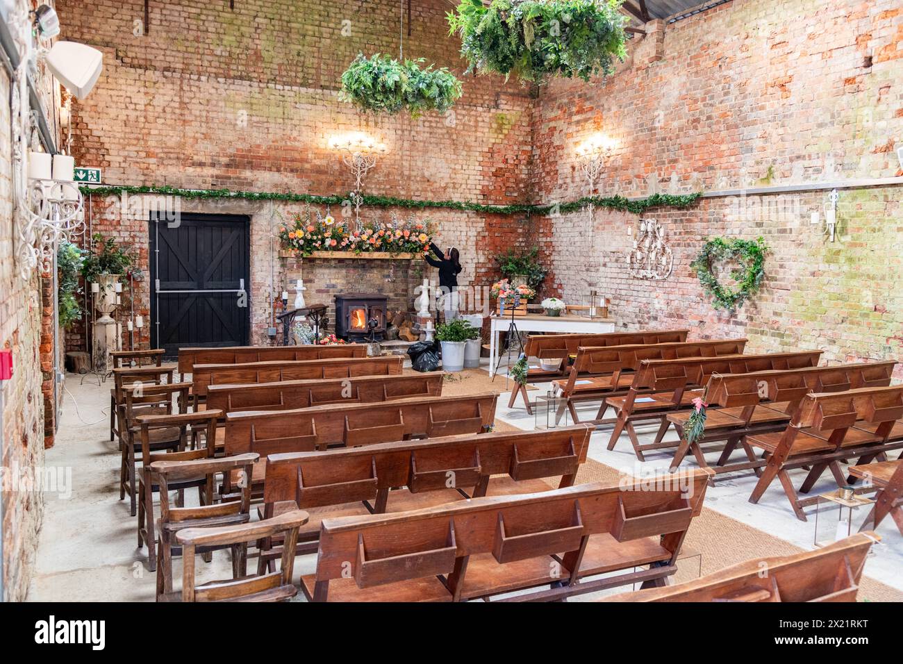 A florist decorating an empty farmhouse barn for a wedding at Botley Hill Farm in Surrey, UK Stock Photo