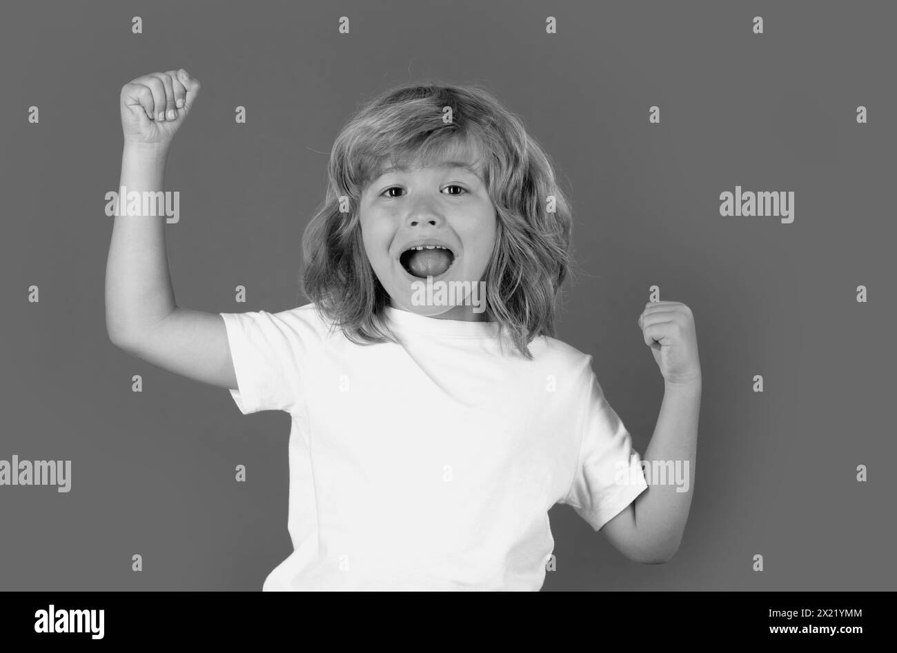 Excited kid celebrating victory on studio isolated background. Surprised face, amazed emotions of child. Rejoicing, yes gesture and success concept. Stock Photo