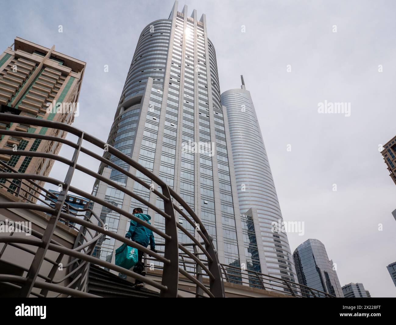 Deliveroo  delivery worker walking up stairs at JLT Jumeirah Lake Towers, Dubai, United Arab Emirates Stock Photo