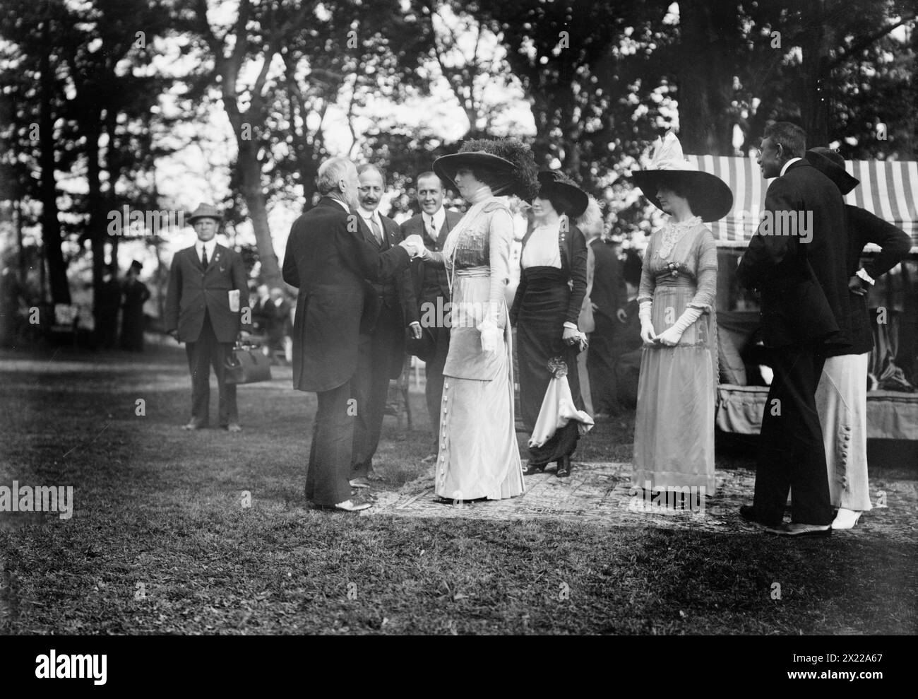 Oscar Straus at B. Cochran's [i.e., Cockran], 1912. Shows Oscar Straus (1850-1926), Bull Moose Party candidate for governor of New York in 1912; shaking hands with Mrs. B. Cochran while Eleanor B. Roosevelt looks on. Event took place at the country home of politician William Bourke Cockran (1854-1923), Port Washington, Long Island, New York State. Stock Photo