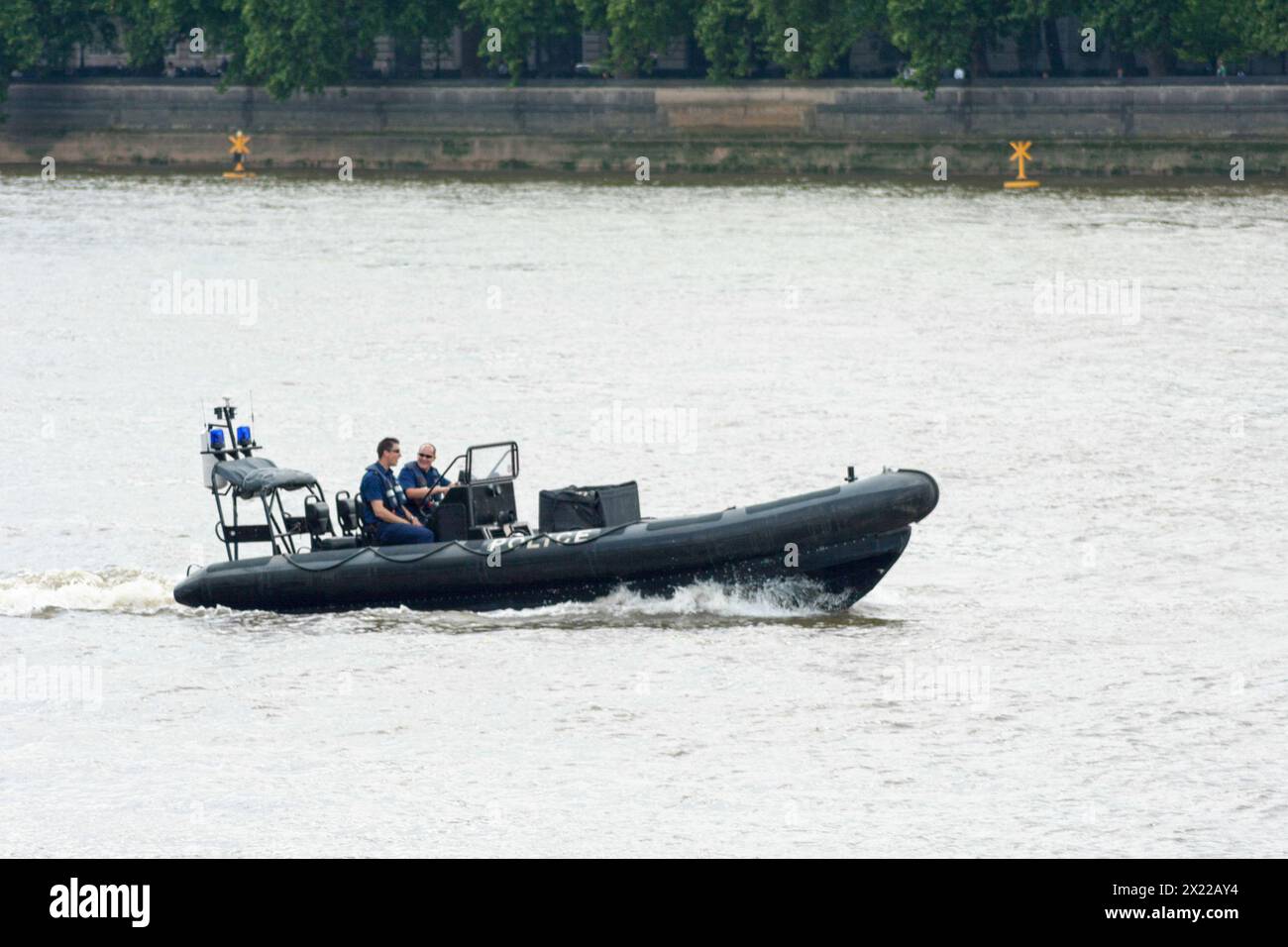 London, England - June 05 2007: Two police officers from the “Marine Police Force” patrolling the Thames River with an inflatable raft near the House Stock Photo