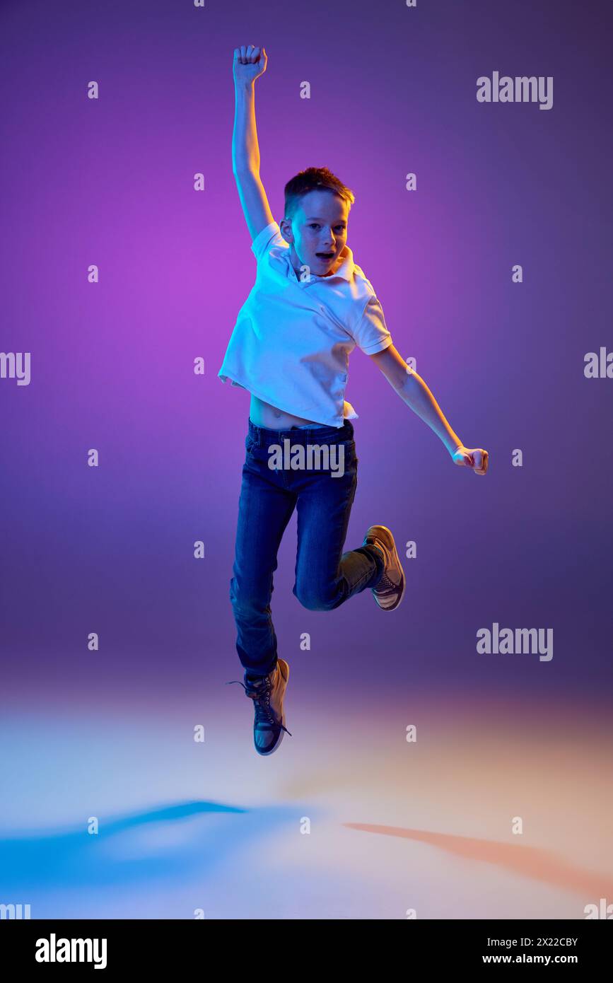 Summer break. Young boy in casual outfit jumping raising hands of joy ...