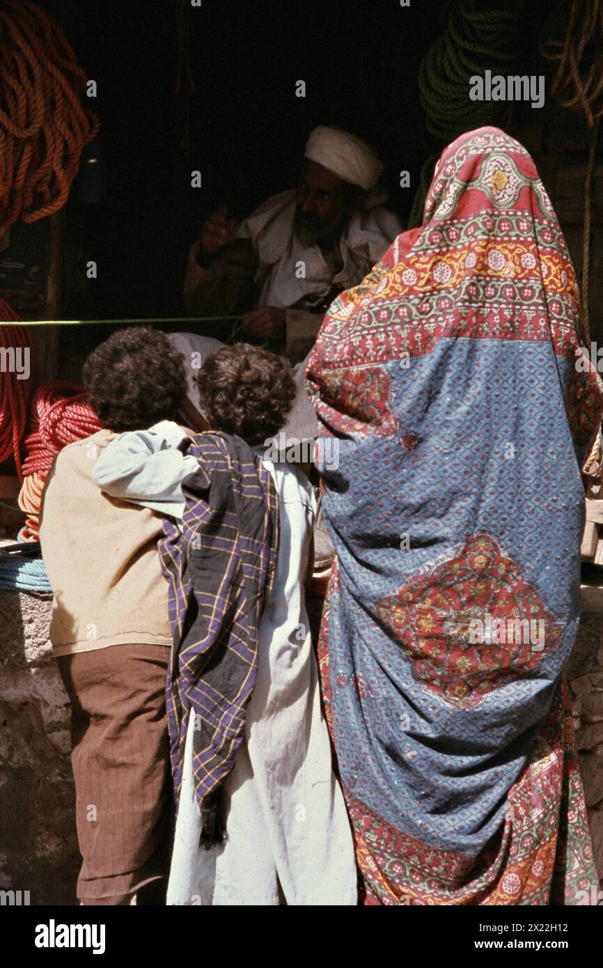 A mother in traditional costume with two children shopping in the souk ...