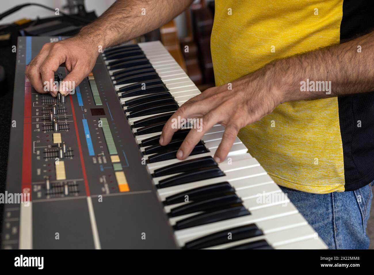 Hands of a Latin American electronic technician verifying the operation of an electric piano recently repaired in the service center. Concept repair, Stock Photo
