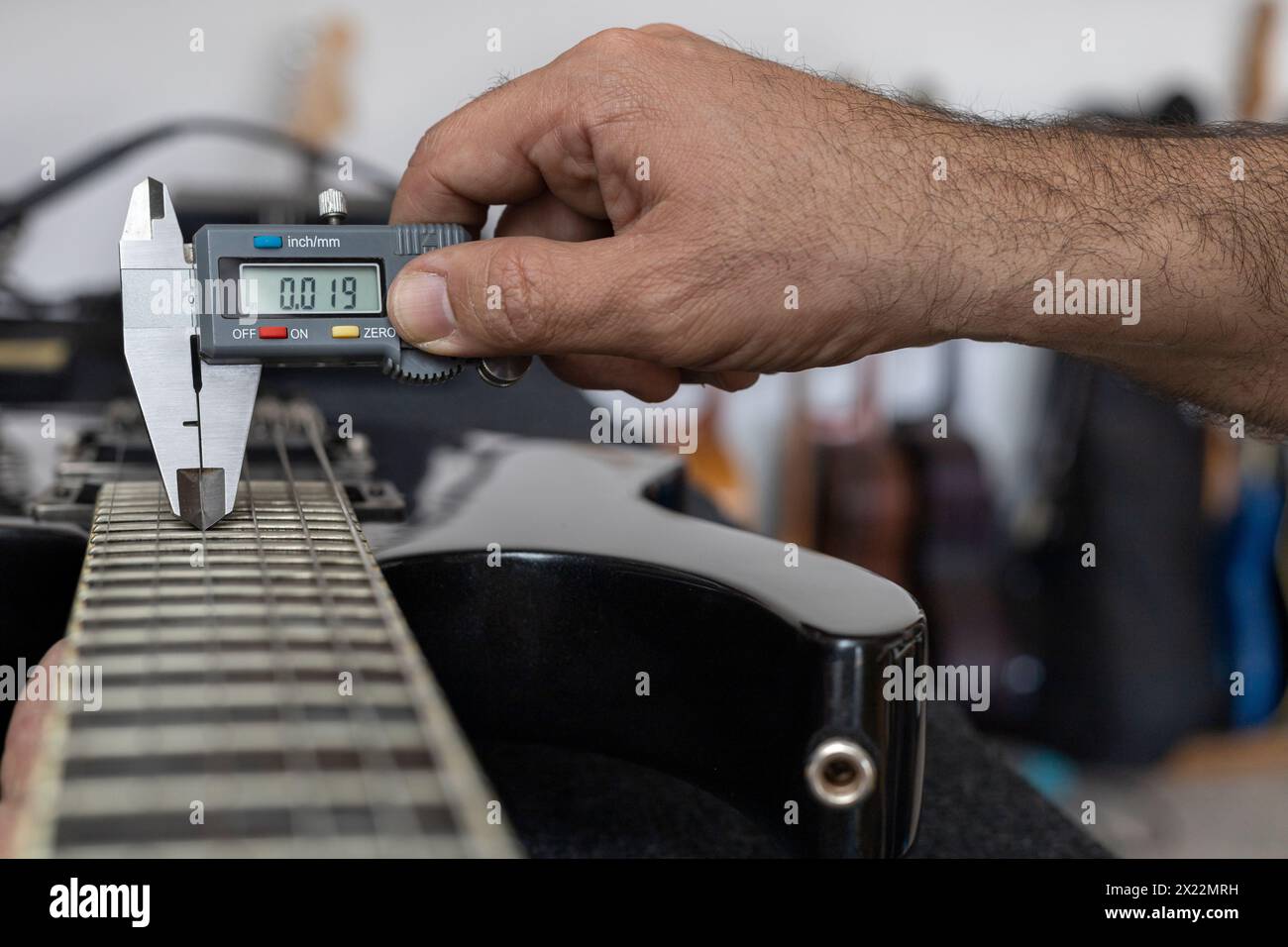 Latin American luthier calibrates the strings of an electric guitar ...
