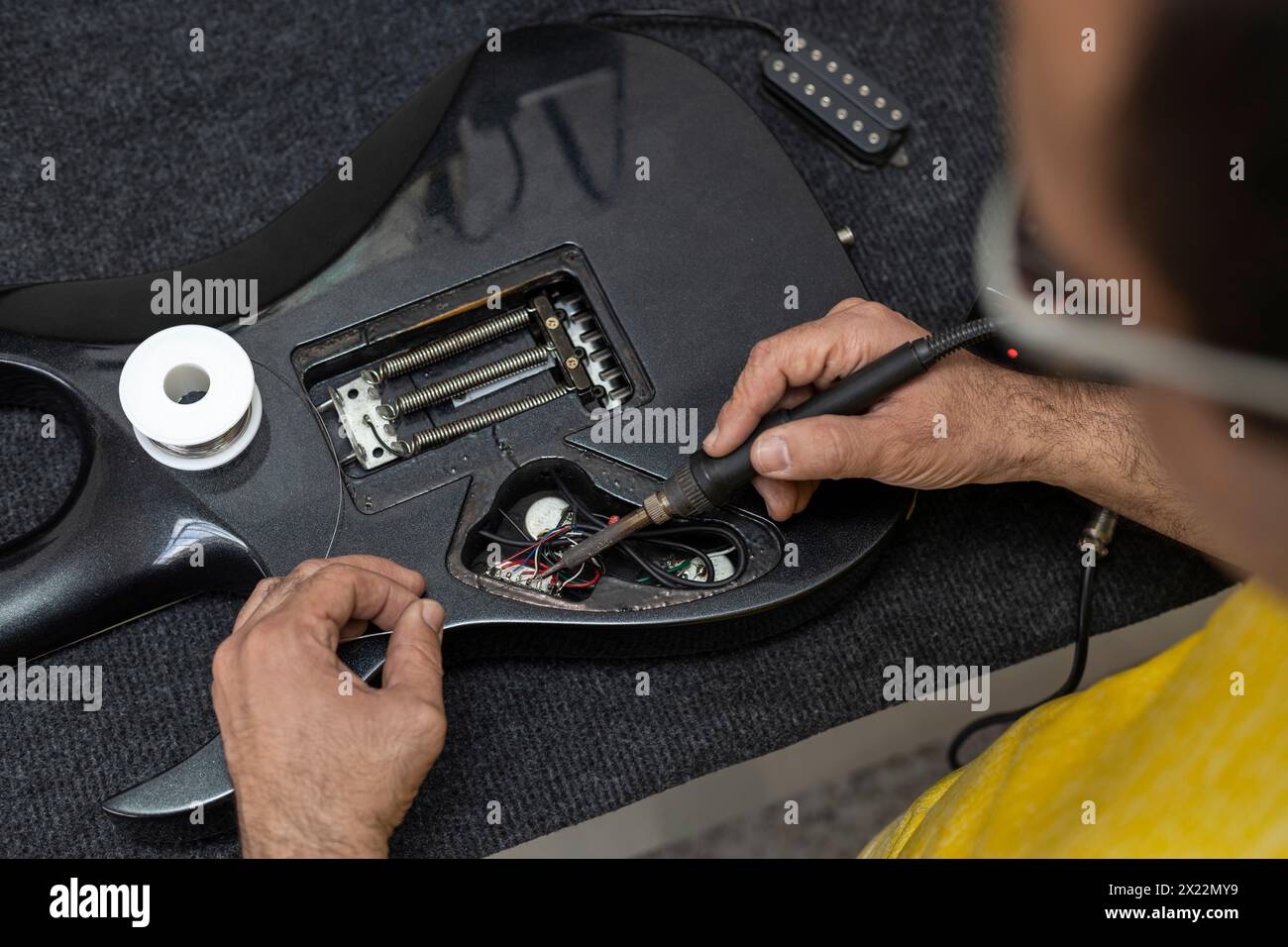 Latin American luthier's hands soldering with a soldering iron and tin