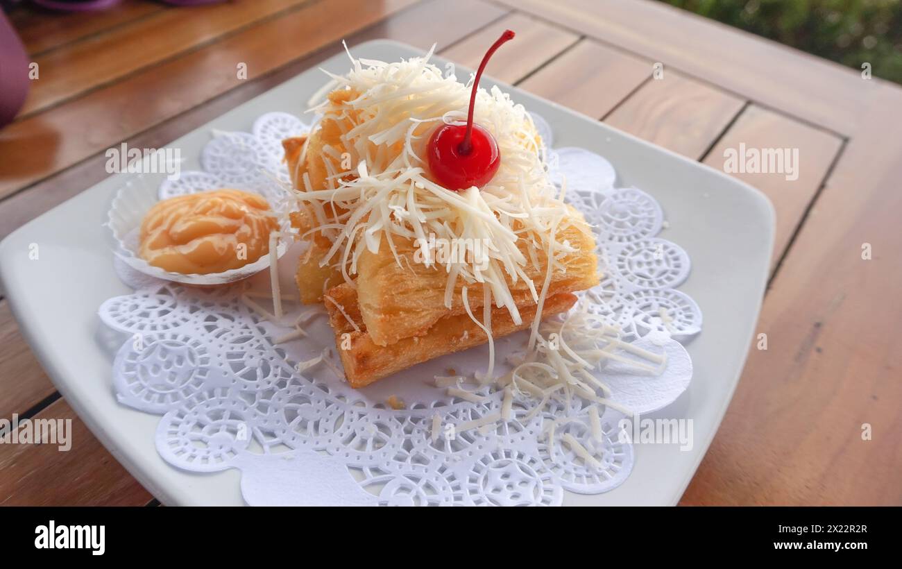 Fried cassava topped with grated cheese and cherries Stock Photo