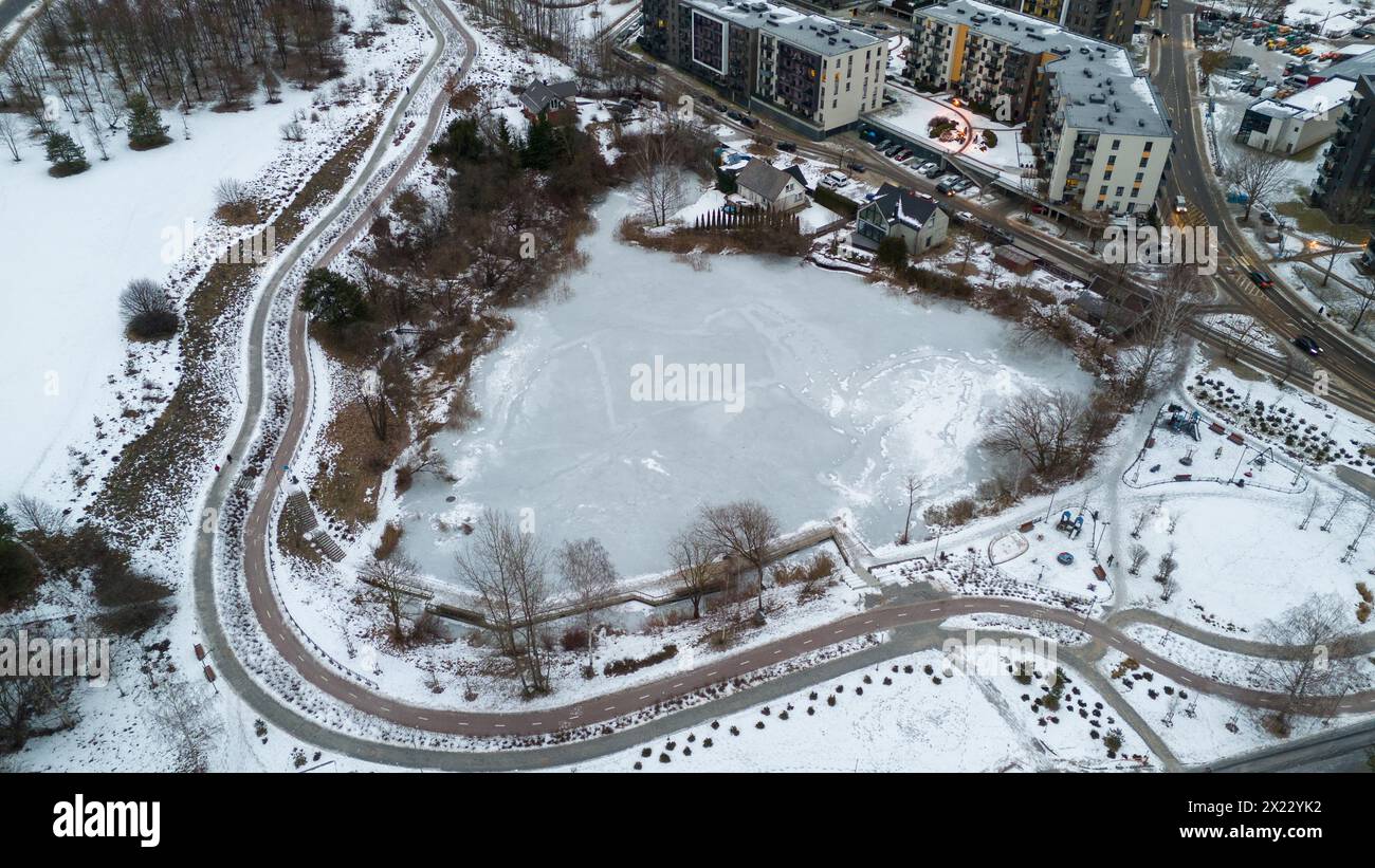 Drone photography of frozen up pond between houses and streets during winter cloudy morning Stock Photo