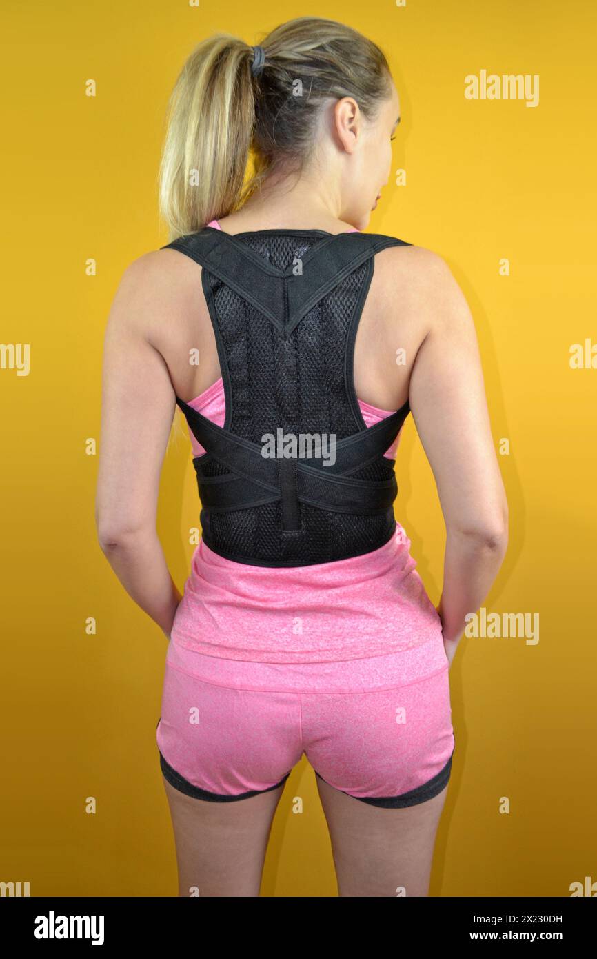 Back and posture support on a beautiful model wearing pink sports outfit Stock Photo