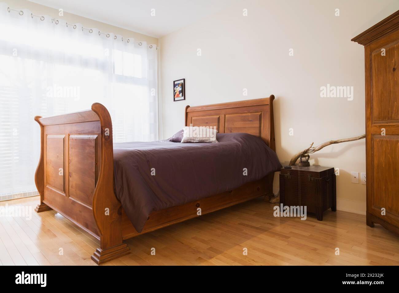 Antique wooden queen size sleigh bed in master bedroom inside a renovated ground floor apartment in an old residential cottage style home, Quebec Stock Photo