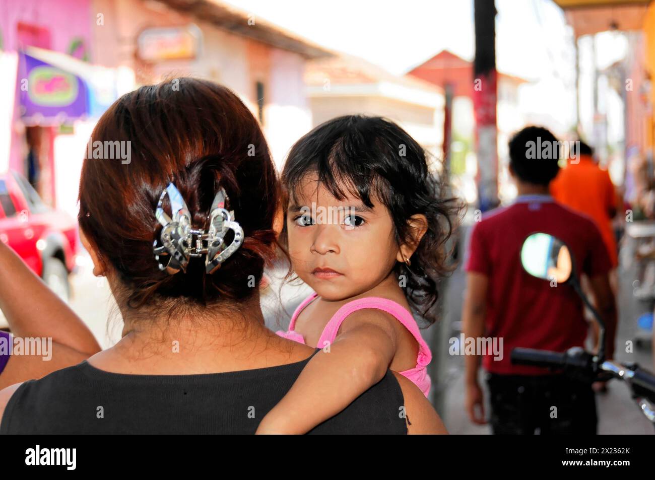 Leon, Nicaragua, A child looks over the shoulder of a woman in a busy city street, Central America, Central America Stock Photo