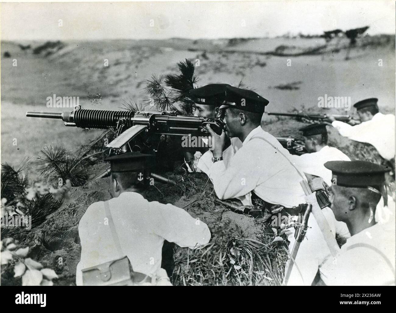 Copy of a photo found on a Japanese captured by Marines on Guadalcanal Island. The Japanese are wearing white uniforms anddress caps, and are posed behind a heavy machine gun. Stock Photo