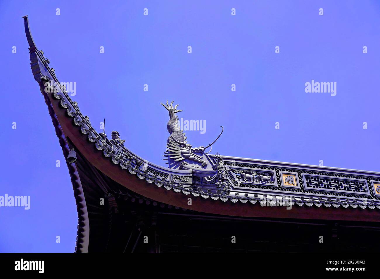 Jade Buddha Temple, Shanghai, detailed view of a temple roof with a dragon sculpture against a blue sky, Shanghai, China Stock Photo