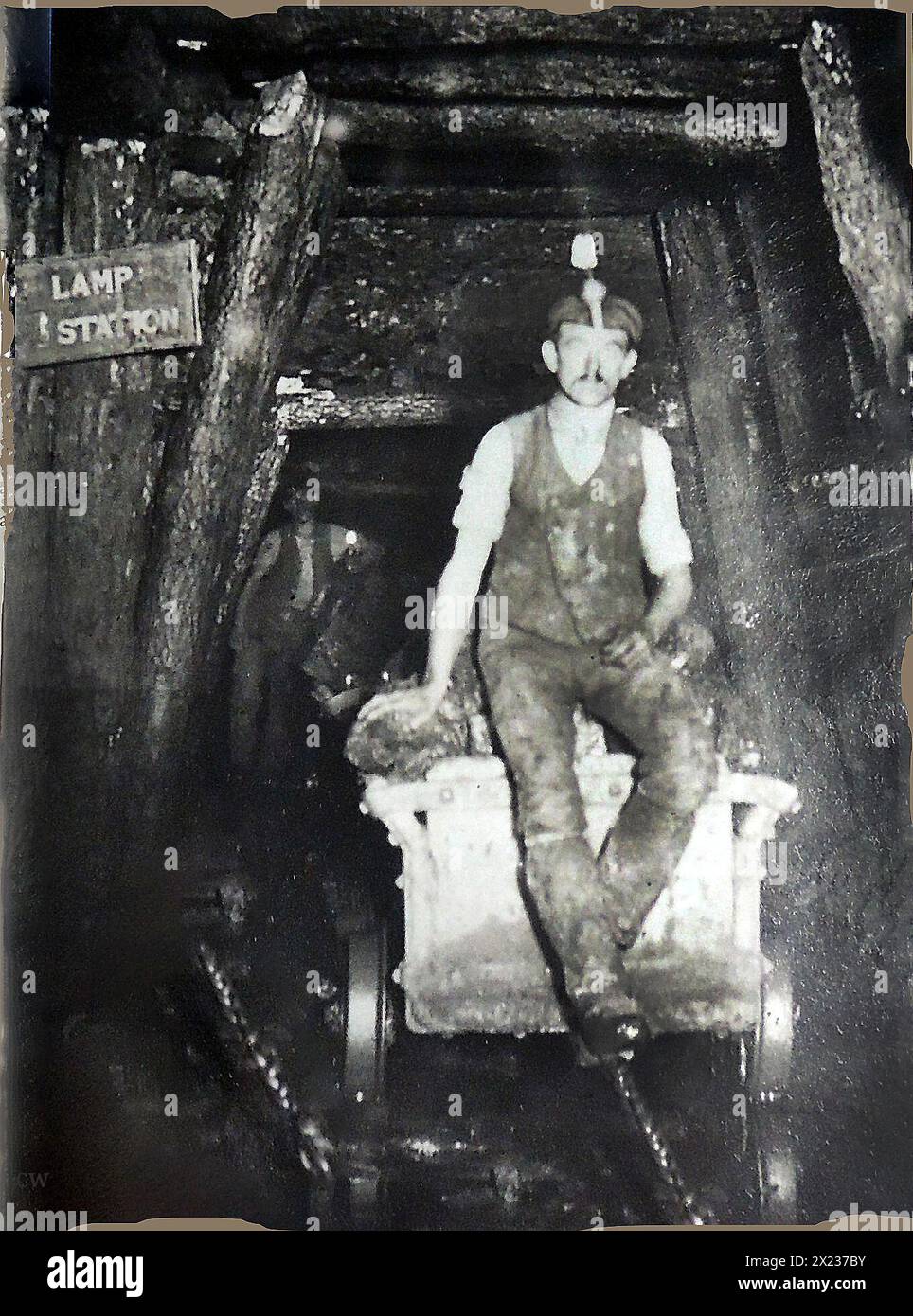 Coal Mining in Britain. An old photograph showing a young coal miner near the Lamp Station, underground at a Welsh coal mine. Stock Photo