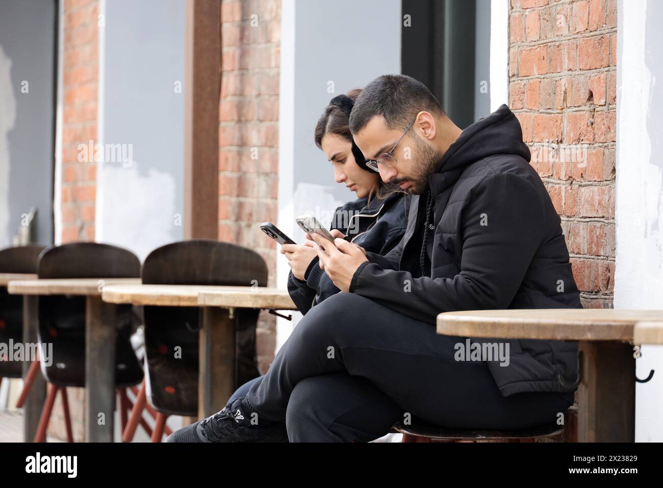 Couple using smartphones while sitting in street cafe at spring Stock Photo