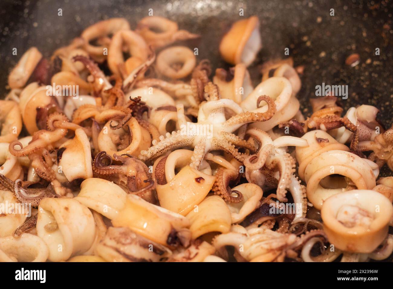 Indulge in the sizzle and aroma of freshly cooked calamari frying in the pan. Experience the culinary artistry and delight of Mediterranean cuisine Stock Photo