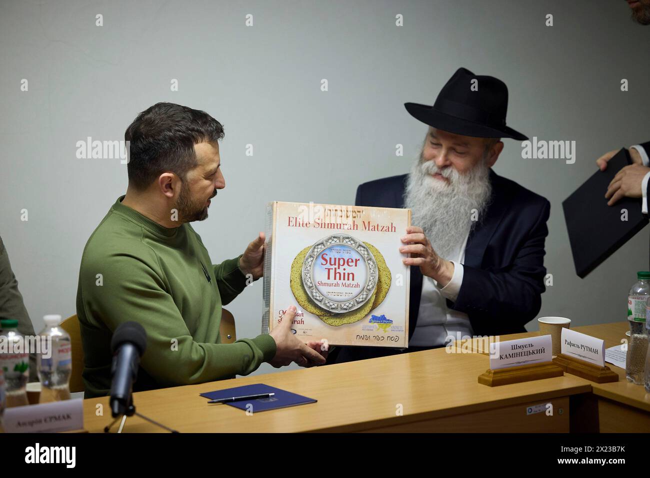 Kiev, Ukraine. 18th Apr, 2024. Ukrainian President Volodymyr Zelenskyy, left, receives a gift of locally made Matzah from Rabbi Shmuel Kaminetsky during a visit to the Shchastia school run by the Chabad-Lubavitch movement, April 18, 2024 in Kyiv Ukraine. Credit: Handout/Ukrainian Presidential Press Office/Alamy Live News Stock Photo