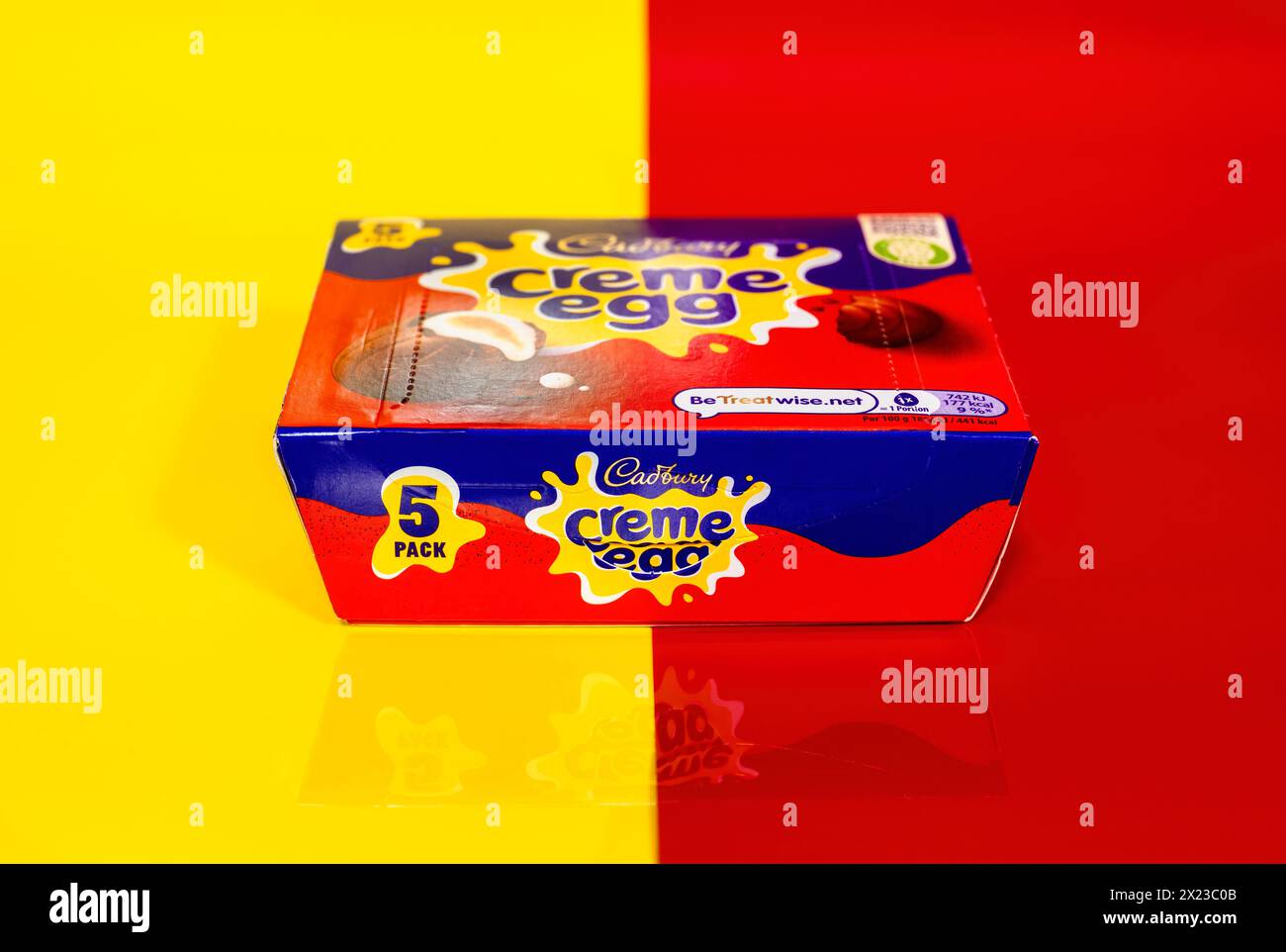 Box of Cadbury Creme Eggs on half yellow and half red background and partial reflection Stock Photo