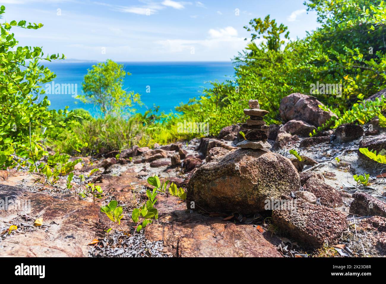 Coastal mountain landscape with stone cairn on a sunny summer day. Praslin, Seychelles Stock Photo