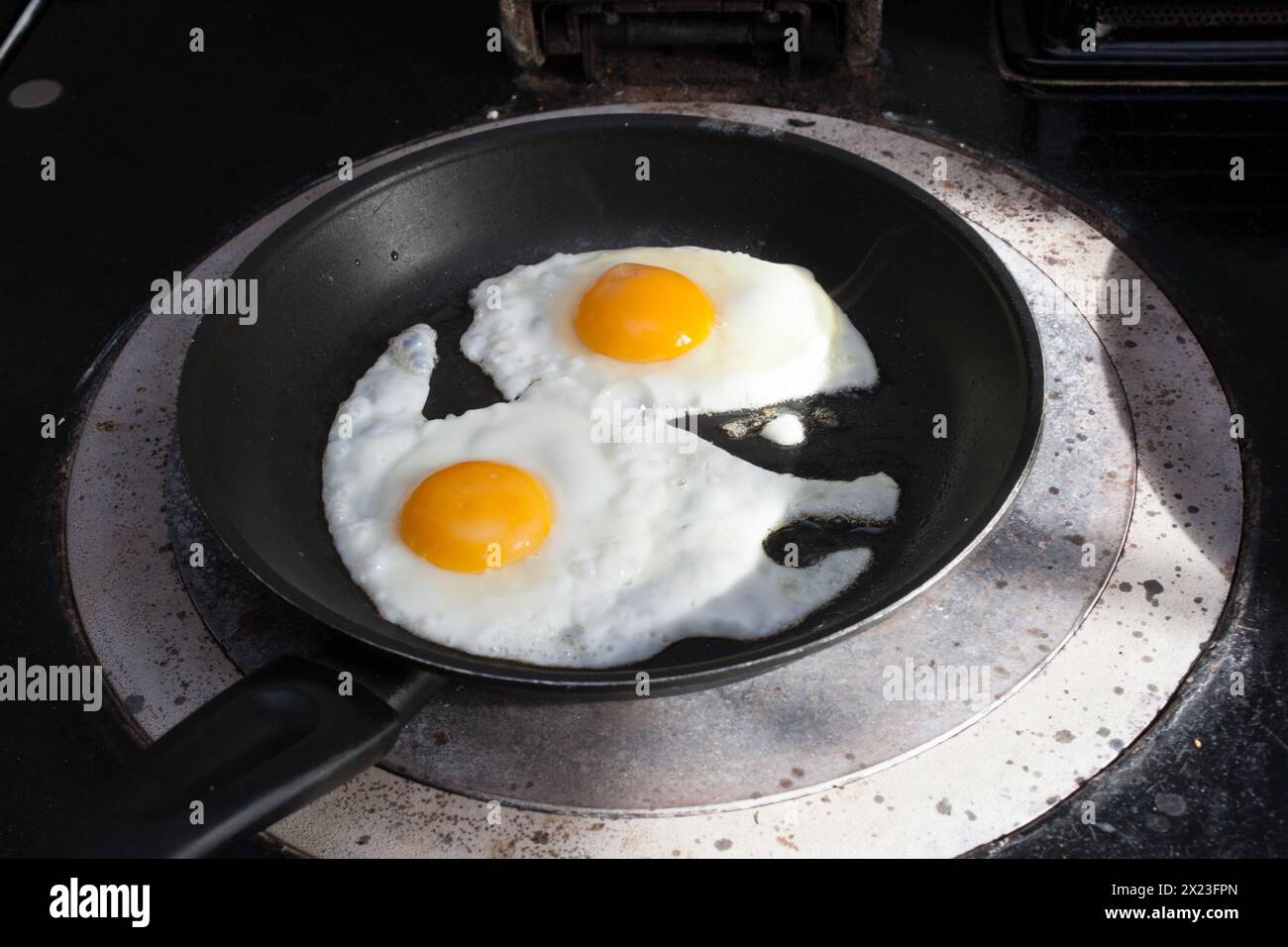 Two hen's eggs frying in a pan on an aga stove Stock Photo