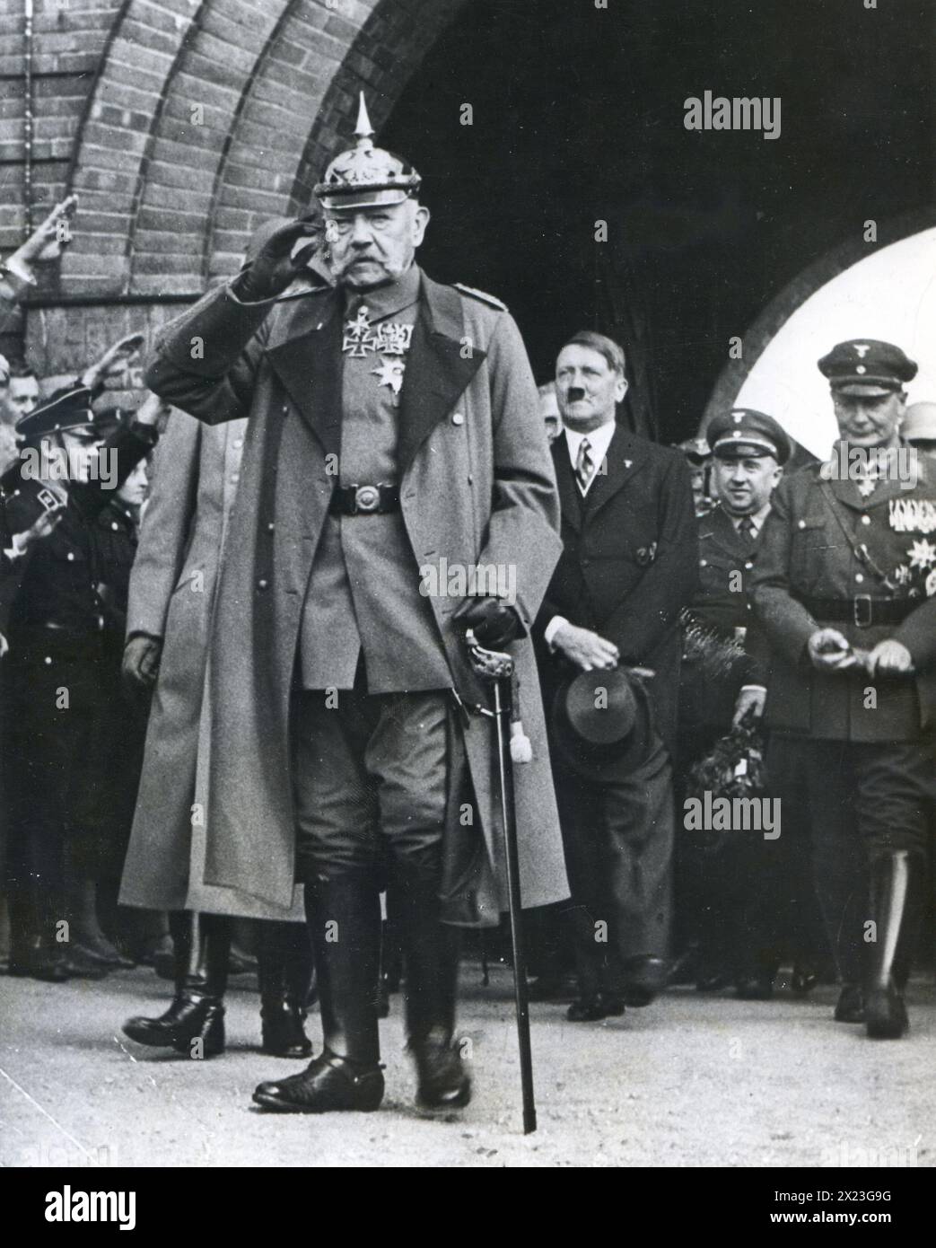 1930's Germany - President of Germany, Paul von Hindenburg salutes in ceremony at Tannenberg Monument. In the background are Adolf Hitler and Hermann Goering. Stock Photo