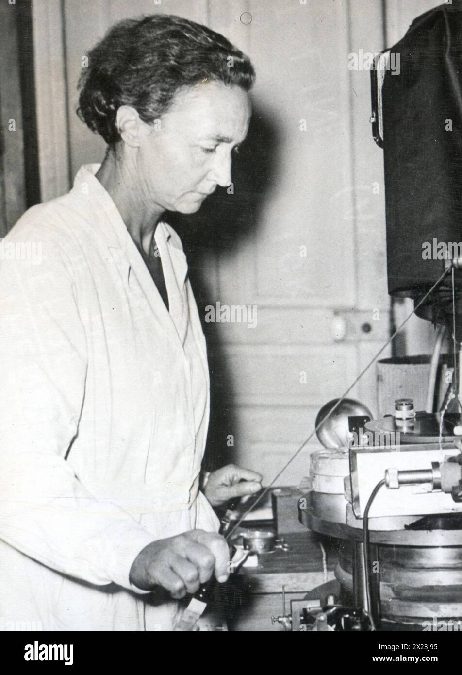 1948 - Pictured at work in her laboratory is Irene Joliot-Curie, nuclear physicist and daughter of the discoverer of radium, Mme. Curie. Stock Photo