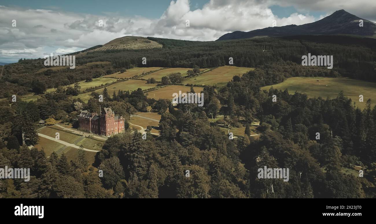Scotland mountains, old castle aerial panning shot: designed landscapes of garden and parks near building. Beautiful woods, hills, valleys in horizon at summer day. Dramatic scenery view Stock Photo