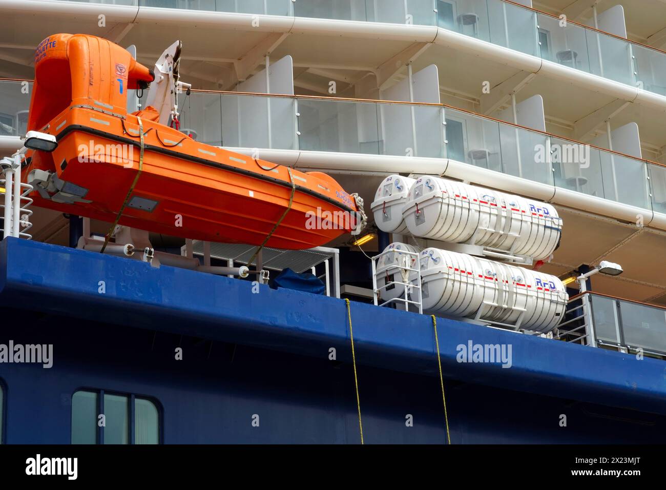 Orange rescue boat and white life rafts of cruise passenger vessel with blue hull. Stock Photo