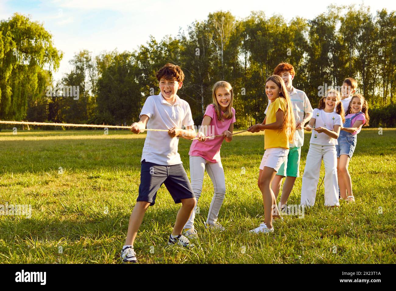 Happy joyful kids playing in tug-of-war with a rope in the summer park ...