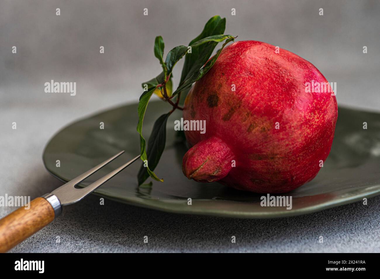 Ripe pomegranate with leaves on a plate Stock Photo