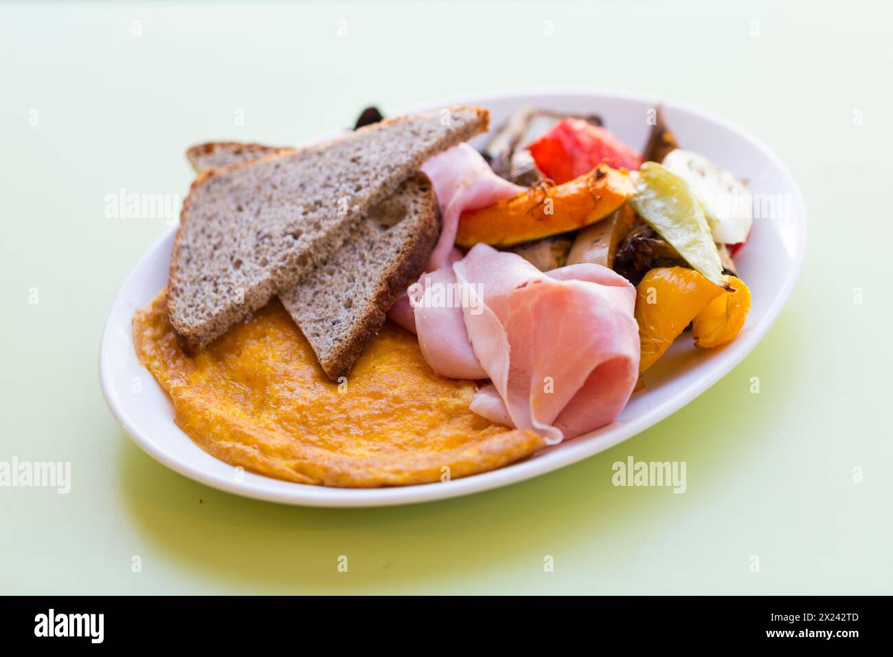 Cheese omelette with brown bread, vegetables and boiled ham Stock Photo