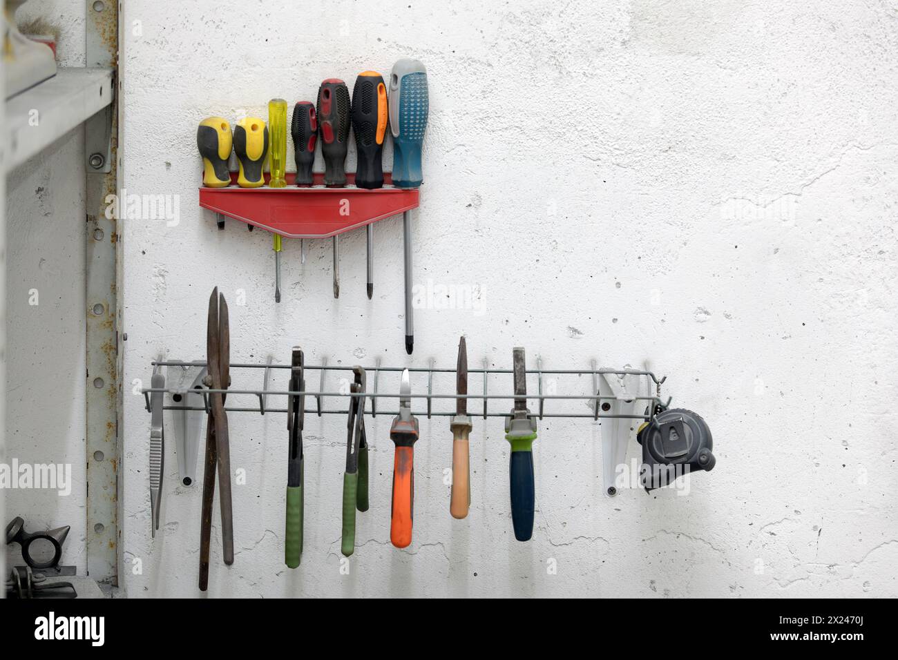 Screwdrivers and other tools hanging on a wall in a workshop Stock Photo