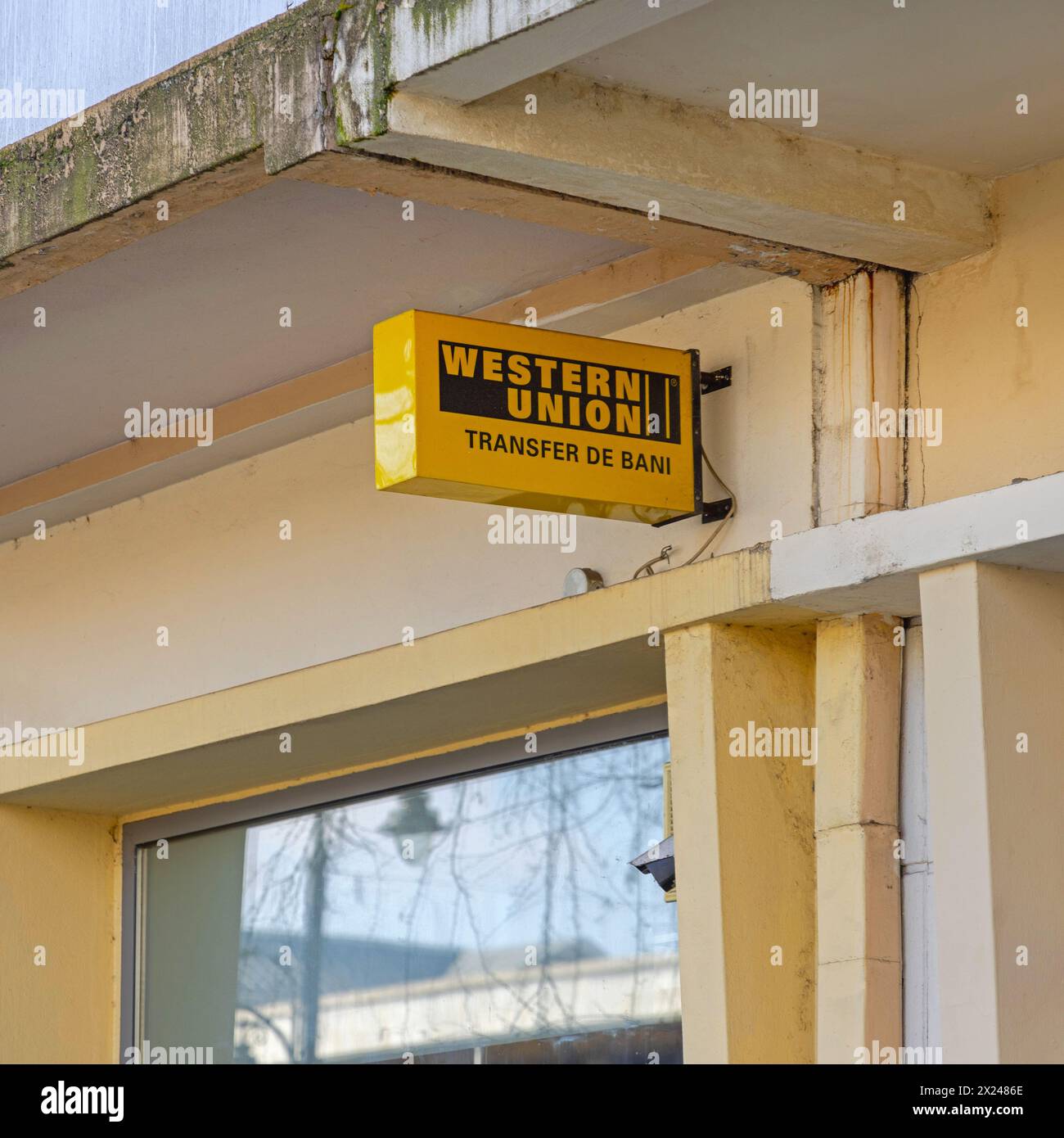 Craiova, Romania - March 16, 2024: Yellow Sign Western Union International Money Transfer at Romanian Bank Building. Stock Photo