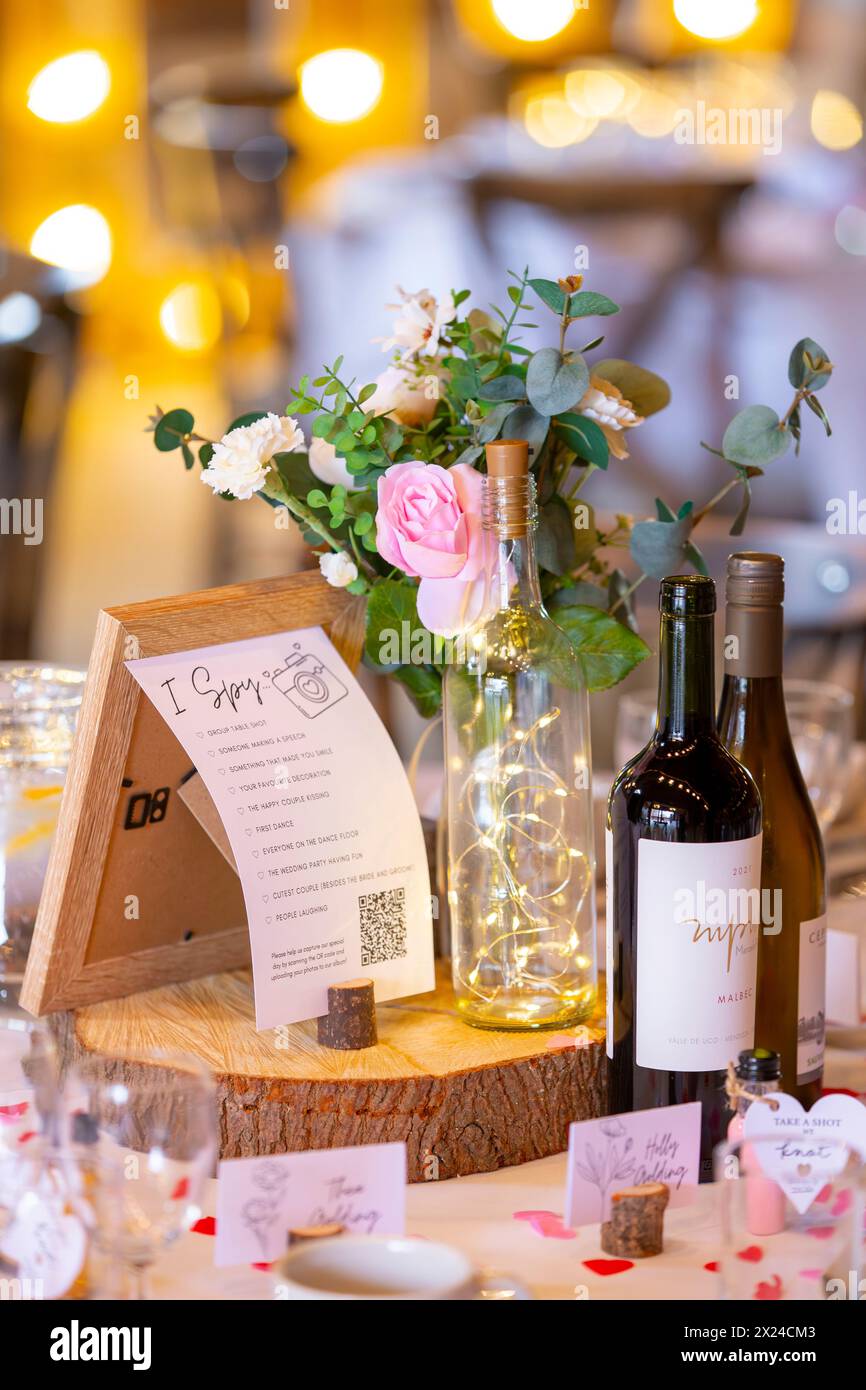 Wedding centrepiece featuring 'I Spy' game, artificial flowers, wine and LED lights in a bottle Stock Photo