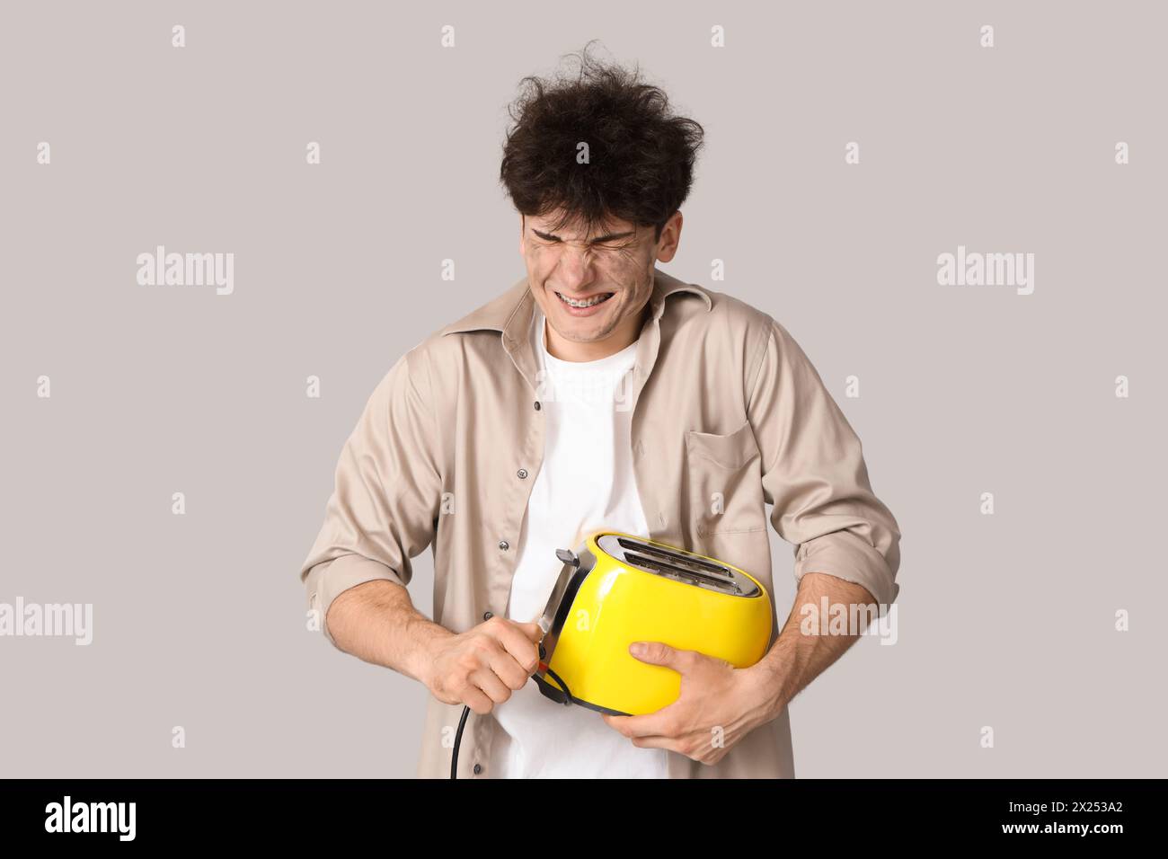 Electrocuted young man with burnt face and toaster on light background ...