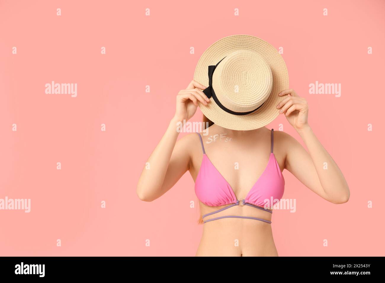 Beautiful young woman with sunscreen cream on her collarbone against pink background Stock Photo