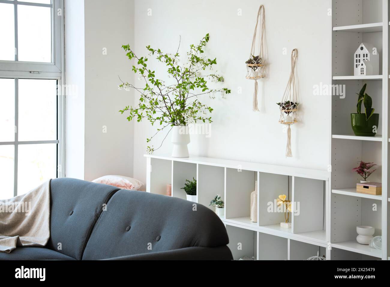 Interior with sofa shelving unit and blooming branches Stock Photo