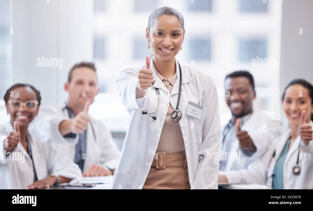 Happy woman, portrait and doctor with thumbs up in meeting for teamwork, success or approval at hospital. Female person, medical employee or group Stock Photo