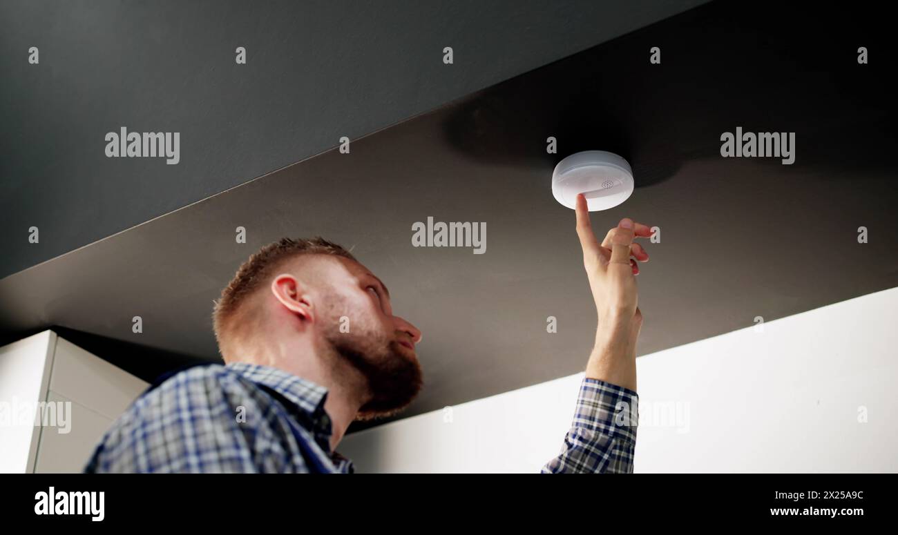 Installing Smoke Detector On Ceiling At Home Stock Photo