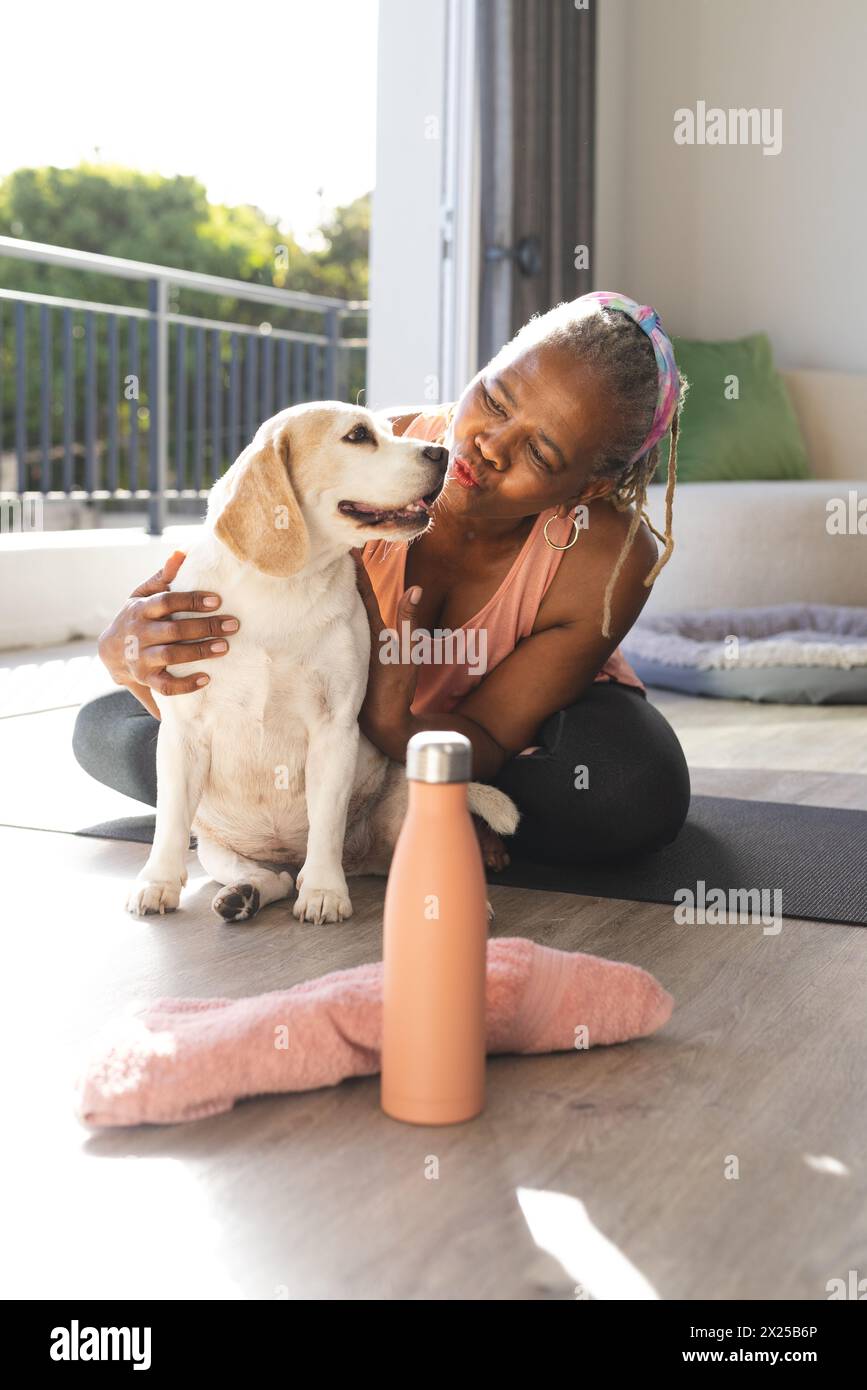 A senior African American woman is sitting at home with her dog Stock Photo