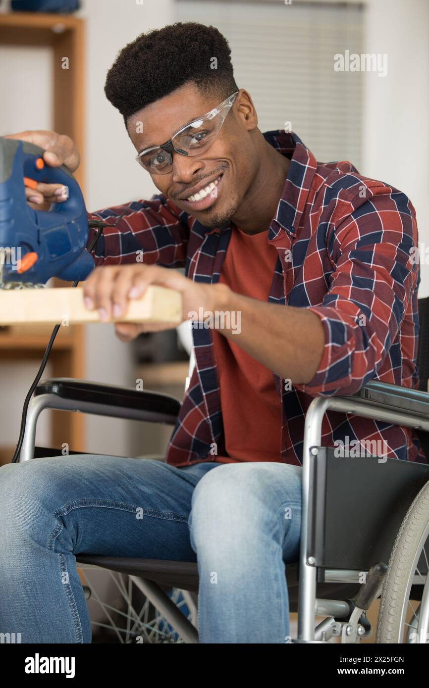 disabled man using electric jigsaw Stock Photo