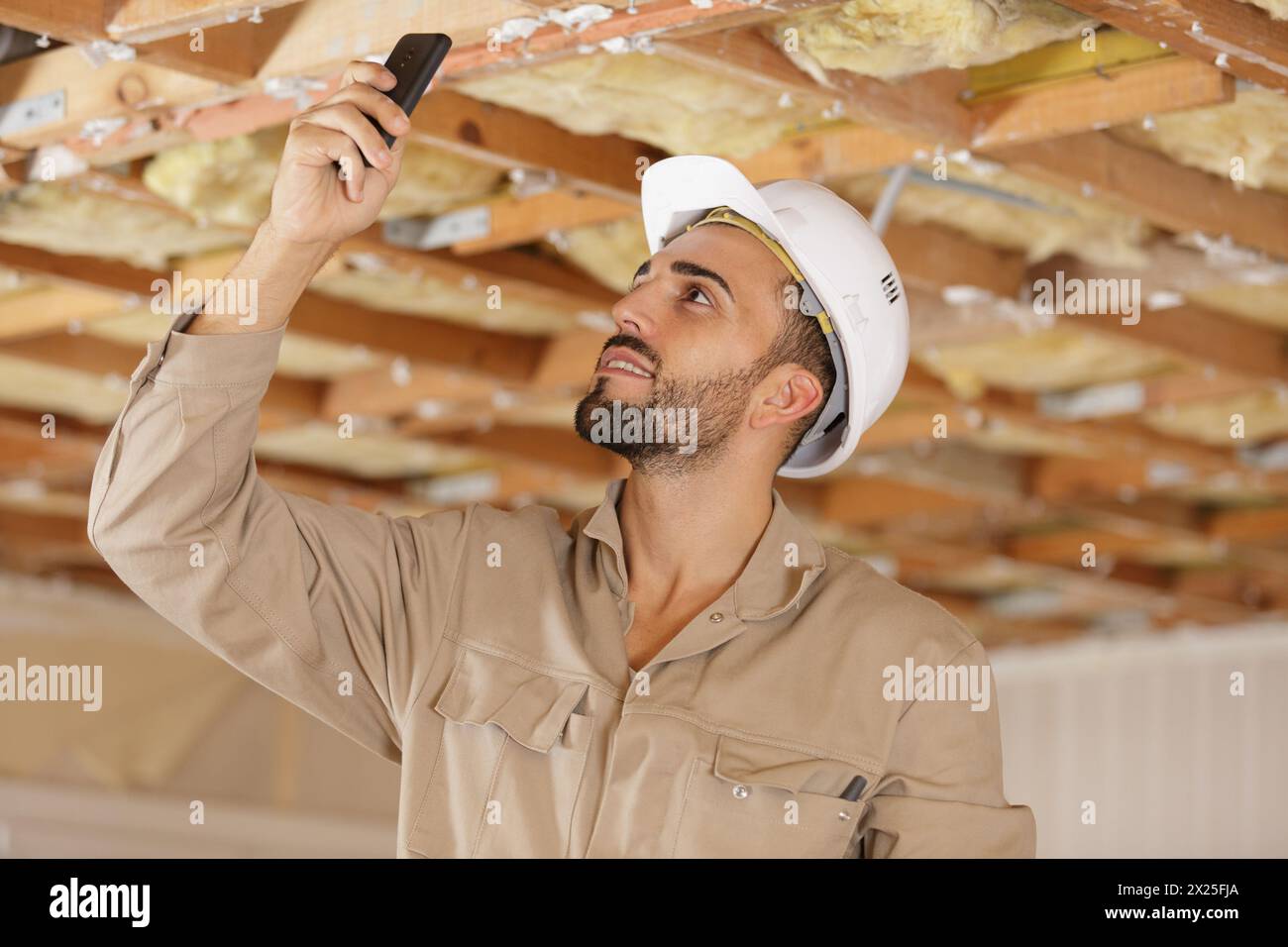 builder using smartphone to photograph ceiling joists Stock Photo