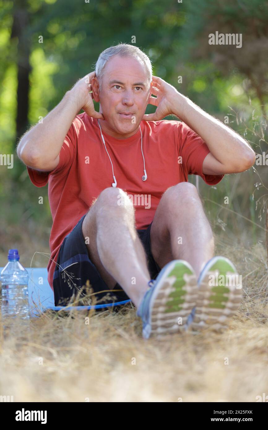 serious middle-age sportsman doing sit-ups outdoors Stock Photo