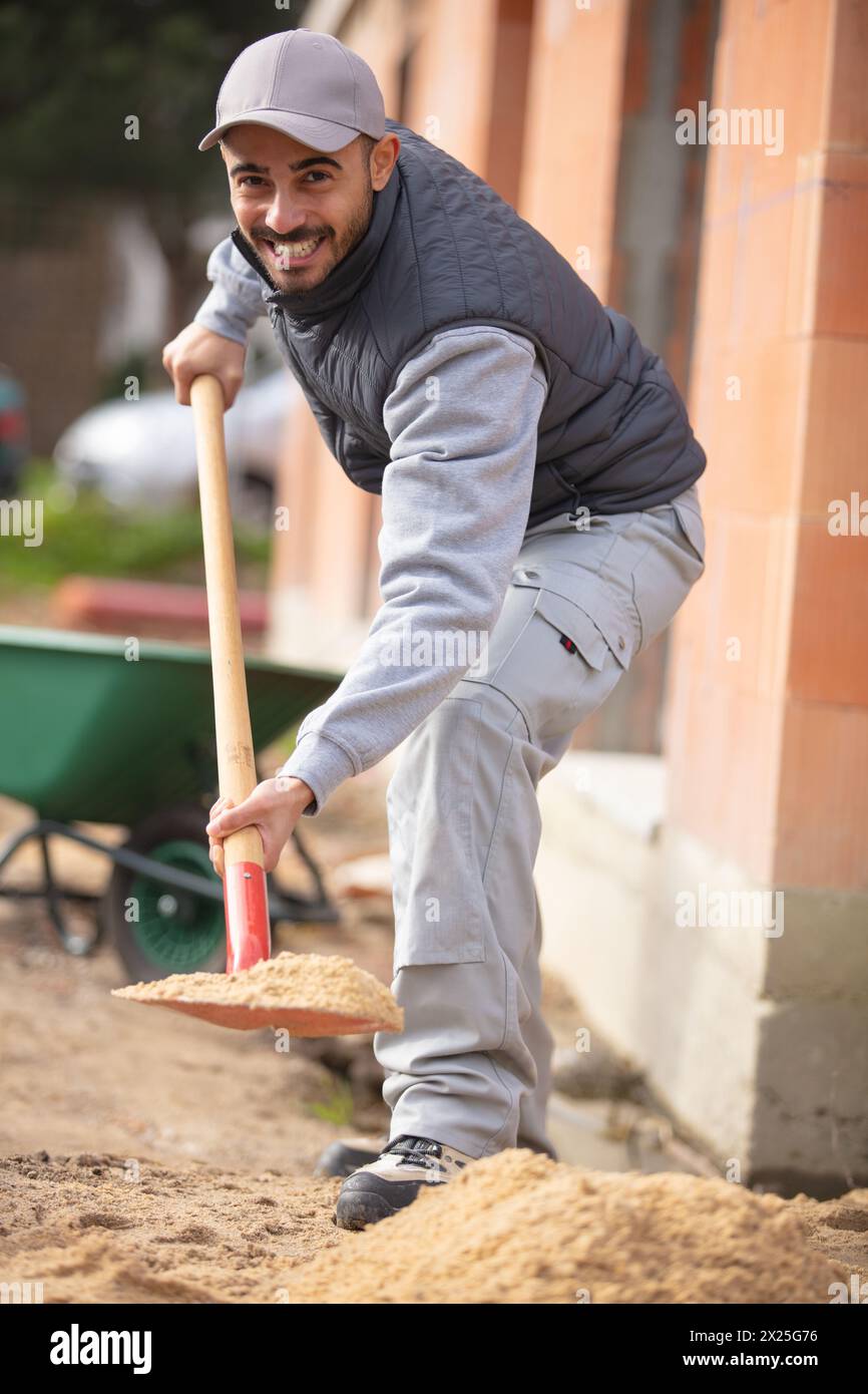 tradesman holding a shovel at construction site Stock Photo
